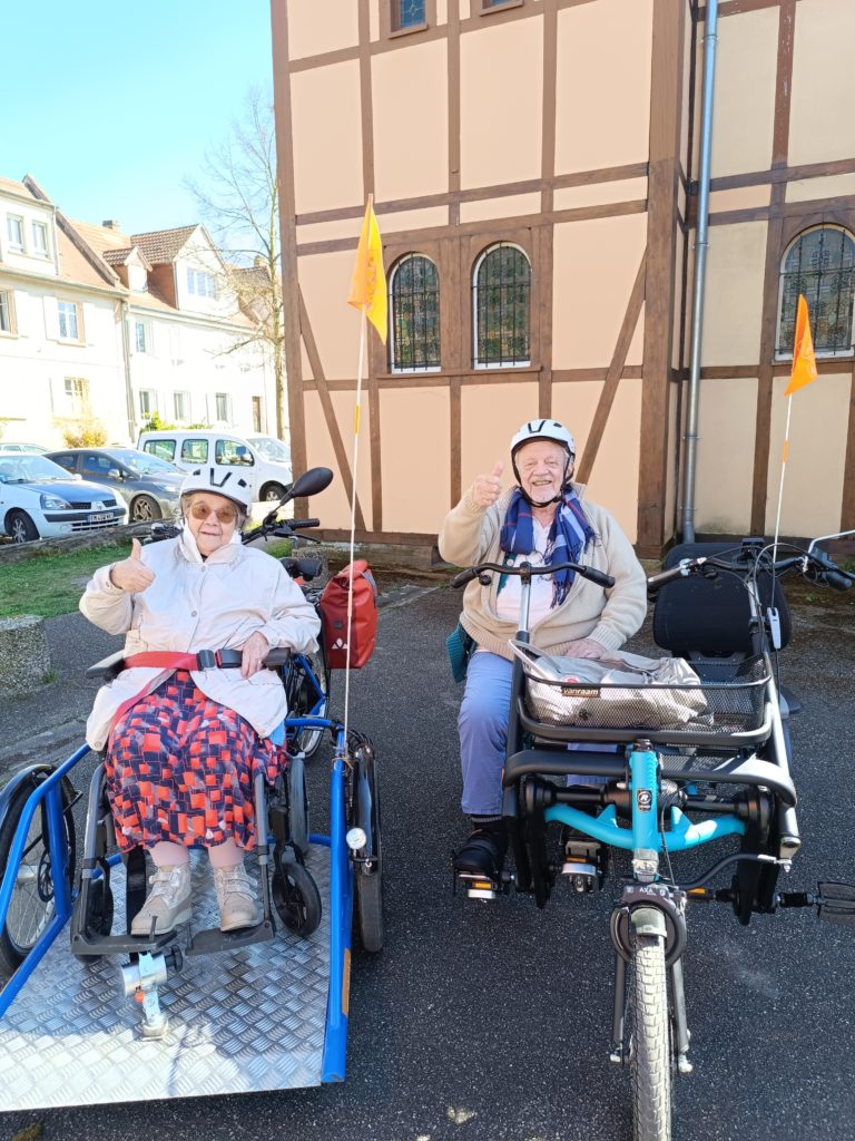 Deux résidents d'EHPAD installés sur nos vélos adaptés qui font des pouces en l'air.