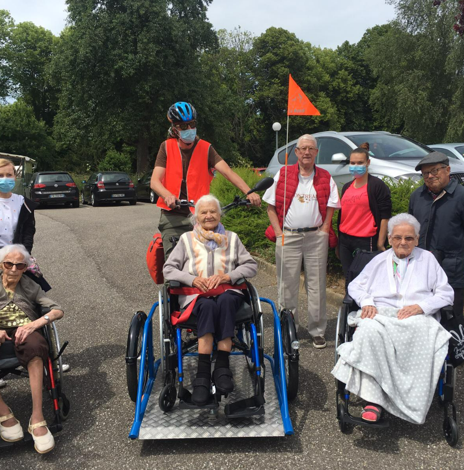 Steve sur son vélo avec plusieurs résidents d'EHPAD à côté.